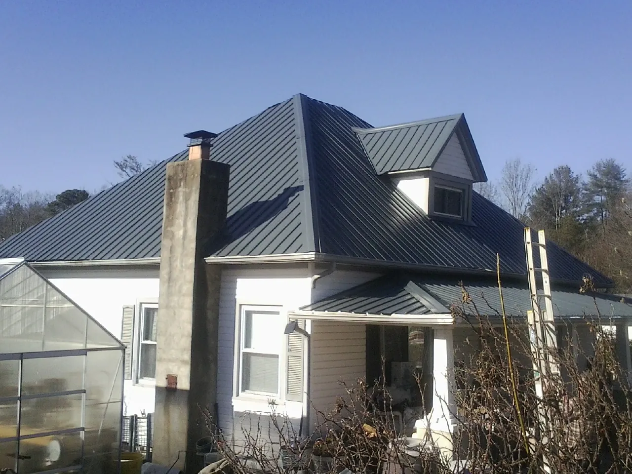 Dark blue standing seam metal roof on a white farmhouse with dormer — Slate & Tile Roof Repair by Roofing Brothers in Greensburg