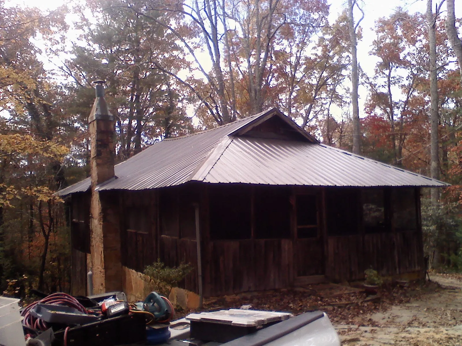 Brown metal hip roof on an old cabin with a stone chimney in Greensburg