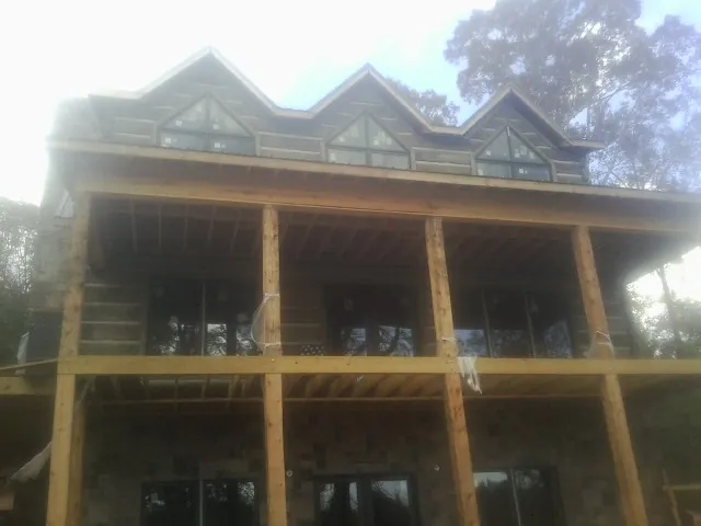 Dormers and porch framing on a large log home under construction — Roof Coating work by our crew in Greensburg