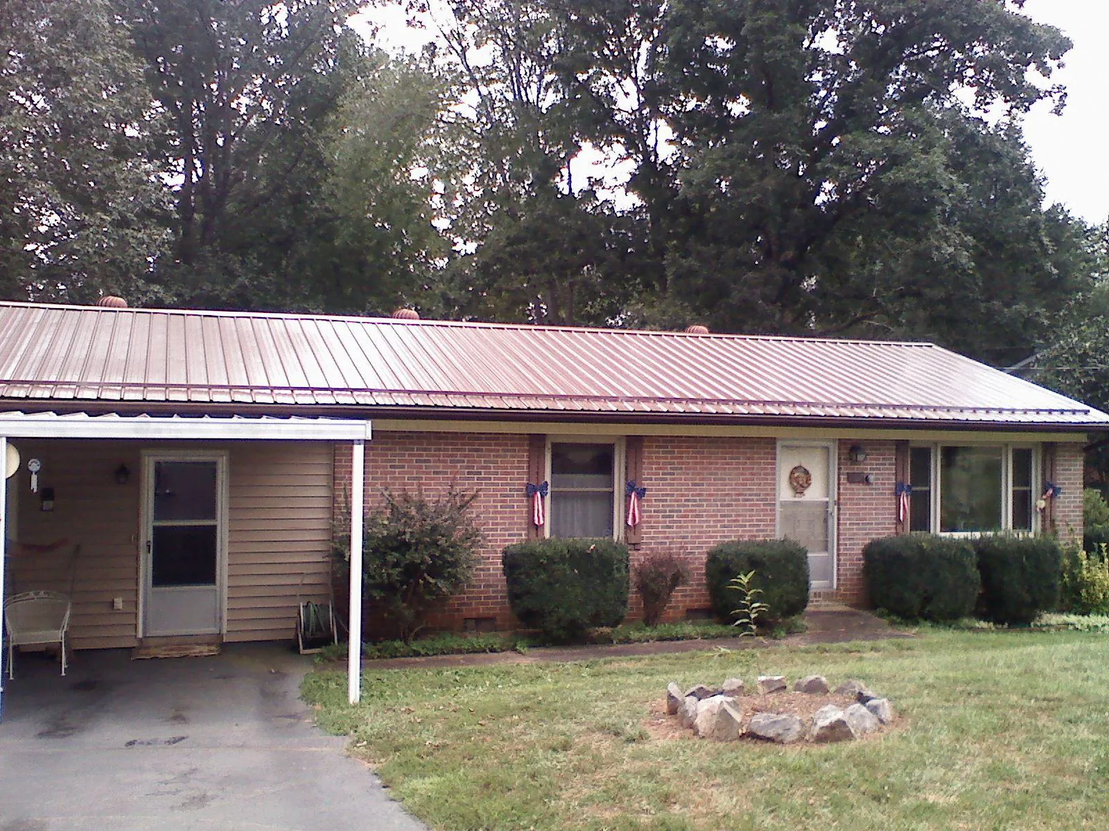 Bronze metal roof and carport on a brick ranch home — Roof Repair work by our crew in Greensburg
